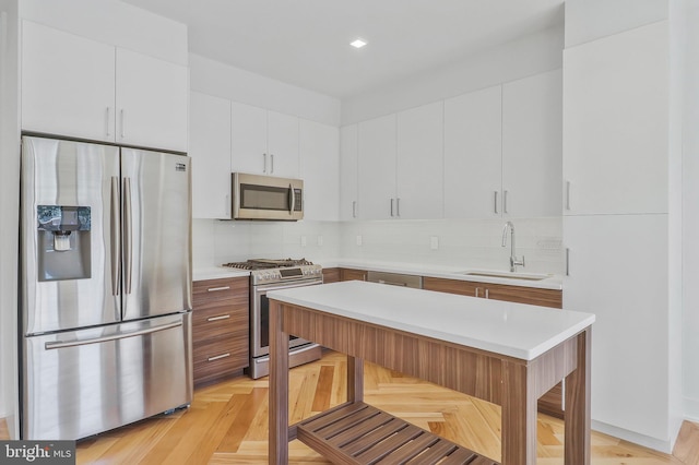 kitchen with white cabinets, appliances with stainless steel finishes, sink, a breakfast bar area, and tasteful backsplash