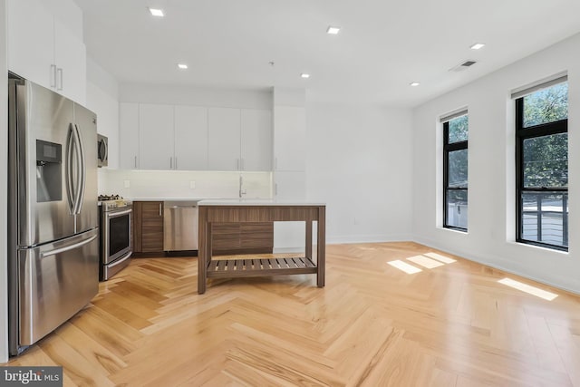 kitchen featuring appliances with stainless steel finishes, tasteful backsplash, light parquet floors, and white cabinetry