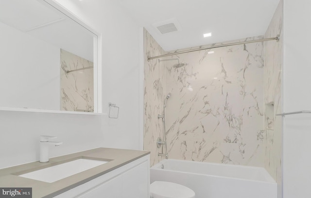 full bathroom featuring vanity, tiled shower / bath, and toilet