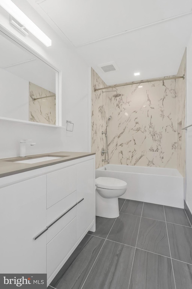 full bathroom featuring tile patterned flooring, vanity, tiled shower / bath, and toilet