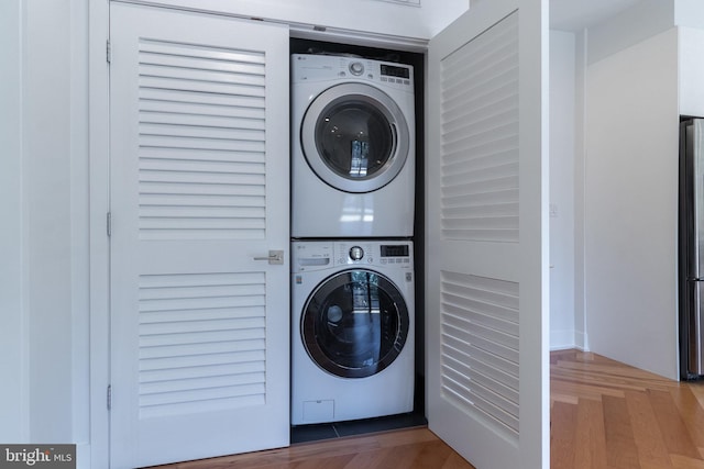 laundry room featuring hardwood / wood-style flooring and stacked washer and clothes dryer