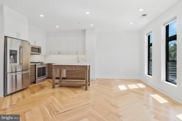 kitchen with stainless steel appliances, decorative backsplash, white cabinets, and light parquet flooring