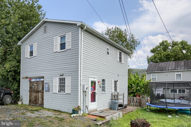 rear view of property with a trampoline