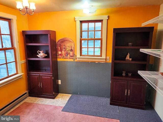 unfurnished dining area featuring a baseboard heating unit, a notable chandelier, tile walls, and a wainscoted wall