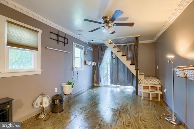 unfurnished living room featuring stairs, crown molding, wood finished floors, and baseboards