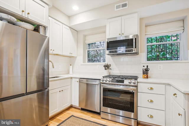 kitchen featuring appliances with stainless steel finishes, light wood-type flooring, white cabinetry, and sink