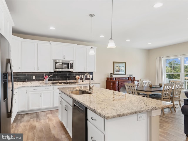 kitchen featuring pendant lighting, a center island with sink, white cabinets, sink, and stainless steel appliances