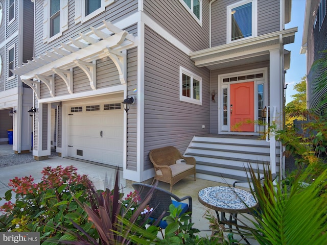 entrance to property featuring a garage and a pergola