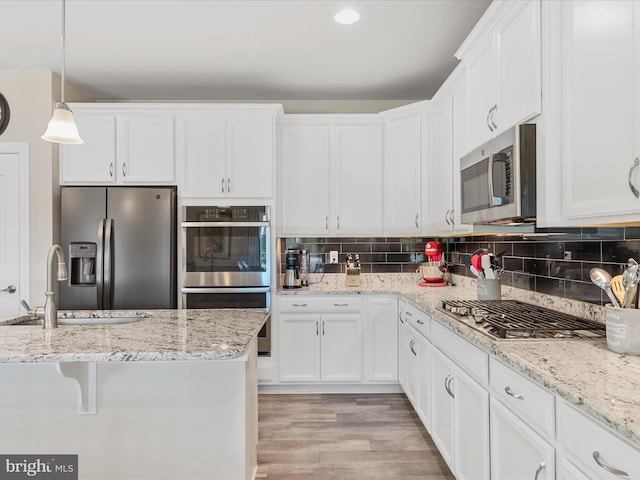 kitchen featuring appliances with stainless steel finishes, white cabinetry, hanging light fixtures, and sink