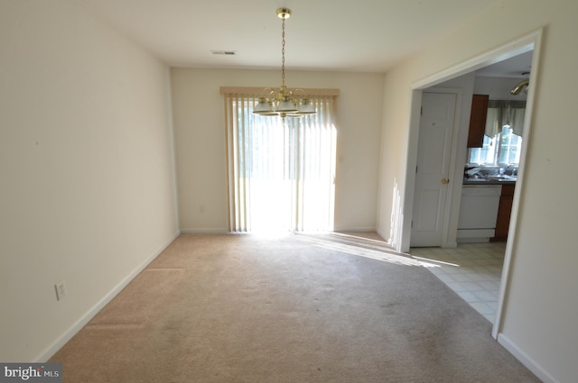 unfurnished dining area with light colored carpet, a healthy amount of sunlight, and a notable chandelier