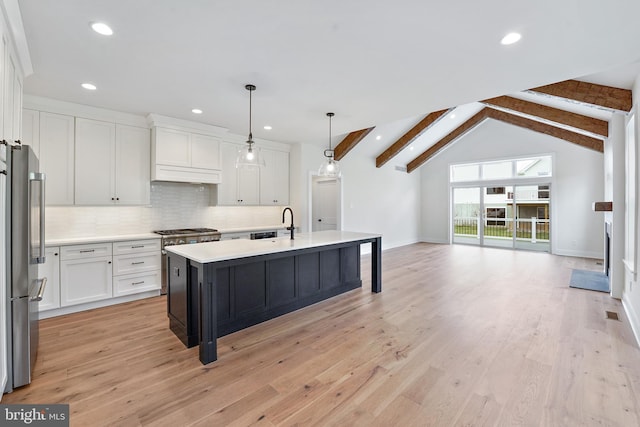 kitchen with pendant lighting, a kitchen island with sink, white cabinetry, light wood-type flooring, and vaulted ceiling with beams