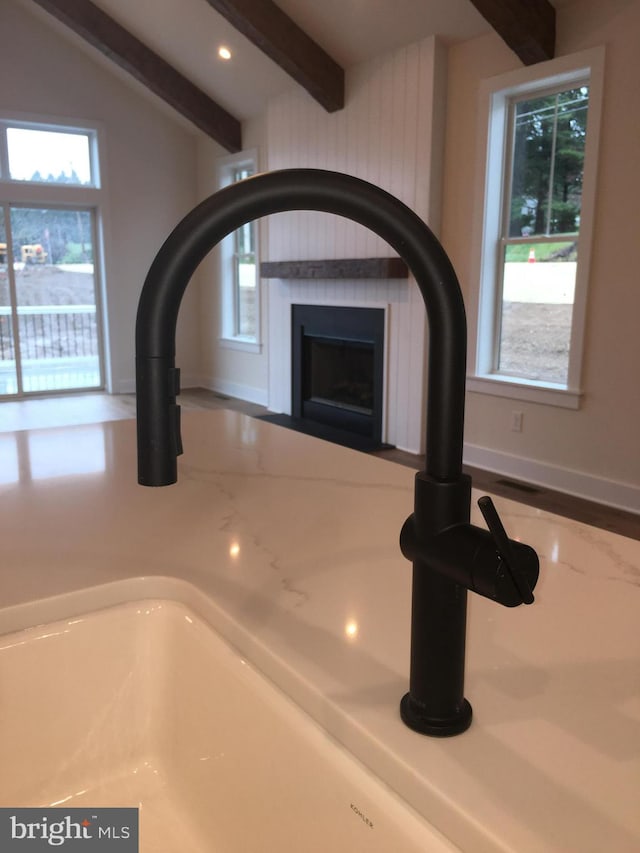 interior details with sink, beam ceiling, and a fireplace