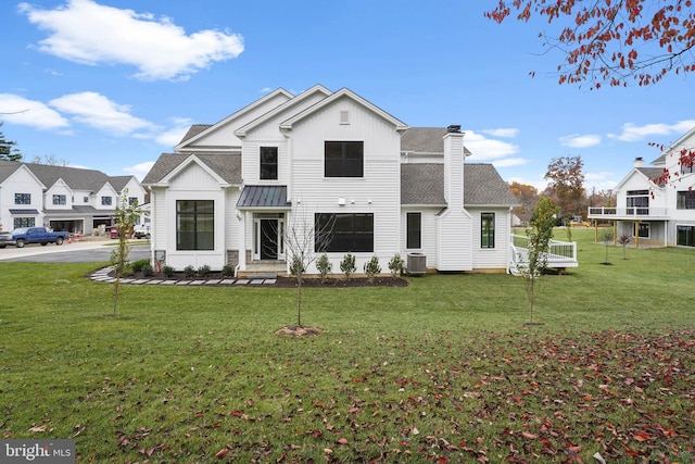 modern farmhouse featuring a front lawn, central AC unit, a chimney, and a shingled roof