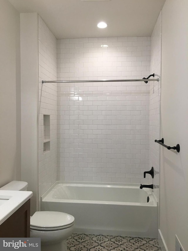 full bathroom featuring tile patterned flooring, toilet, tiled shower / bath combo, and vanity