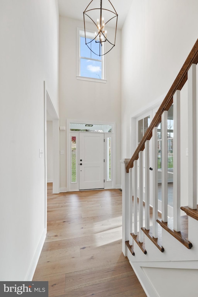 entryway featuring light wood-type flooring, a notable chandelier, and a high ceiling