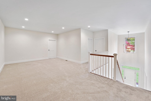 carpeted empty room featuring an inviting chandelier