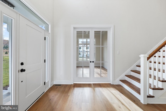 foyer entrance featuring a healthy amount of sunlight, french doors, and light hardwood / wood-style floors