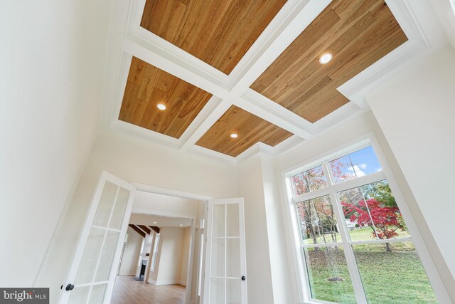 interior details featuring coffered ceiling, beamed ceiling, wooden ceiling, wood-type flooring, and ornamental molding