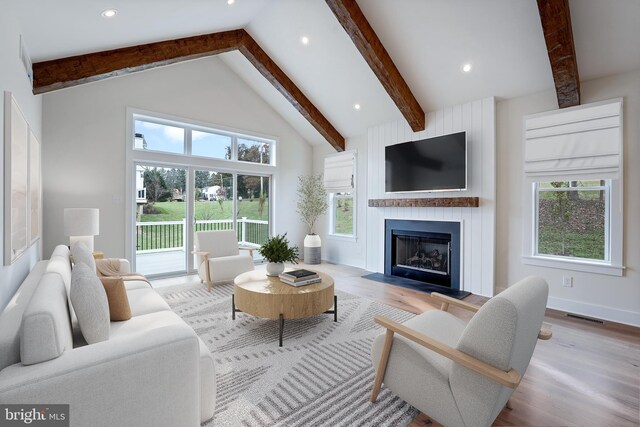 living room with a large fireplace, beamed ceiling, high vaulted ceiling, and light hardwood / wood-style floors