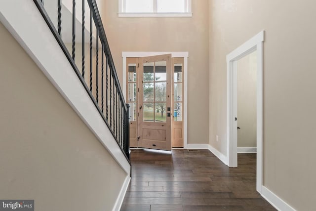 foyer featuring baseboards, stairs, dark wood-style floors, and a high ceiling