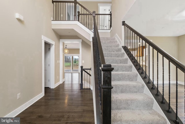 stairs featuring wood-type flooring and a towering ceiling