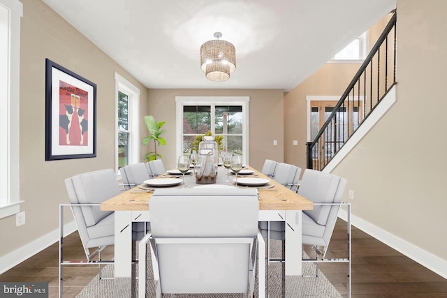 dining area with dark wood-type flooring, stairs, and baseboards