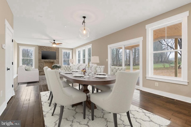 dining area featuring ceiling fan, dark hardwood / wood-style floors, and a fireplace