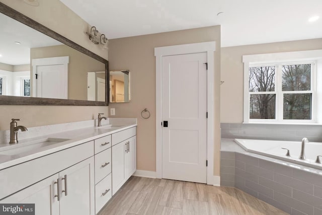 bathroom with tiled tub, hardwood / wood-style flooring, and vanity