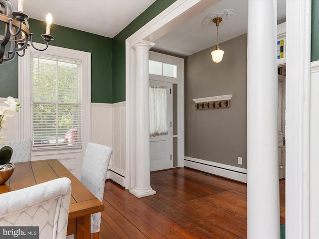 entryway with a chandelier, dark hardwood / wood-style flooring, a baseboard radiator, and decorative columns