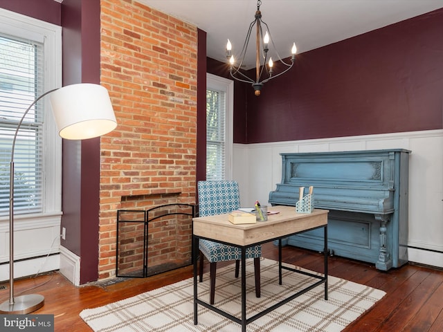 office space featuring baseboard heating, plenty of natural light, hardwood / wood-style floors, and an inviting chandelier