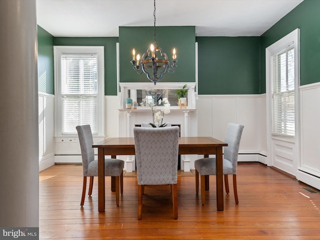 dining space with wood-type flooring, an inviting chandelier, and a healthy amount of sunlight