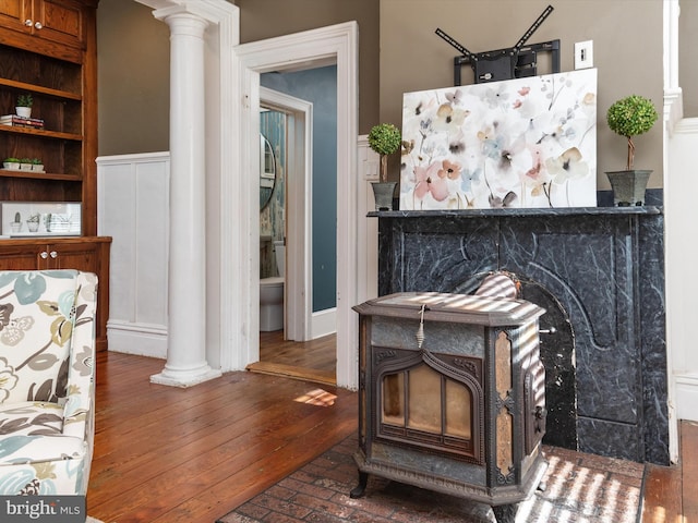 room details with hardwood / wood-style flooring, ornate columns, and a wood stove