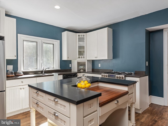 kitchen with stainless steel appliances, white cabinetry, and dark wood-type flooring