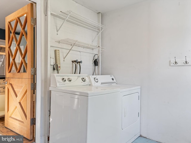 clothes washing area with light wood-type flooring and separate washer and dryer