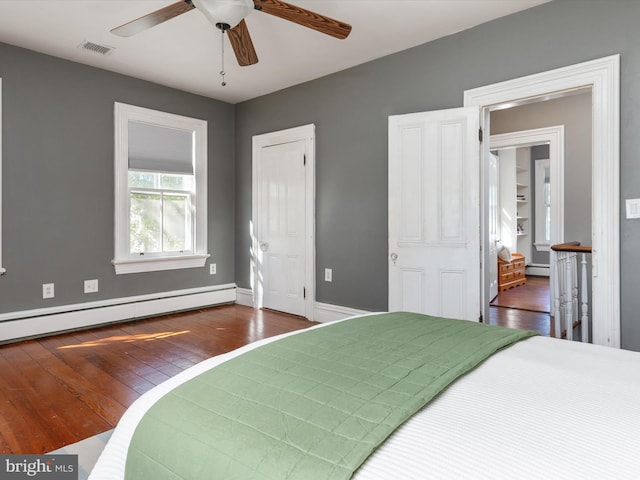 bedroom featuring dark hardwood / wood-style flooring, ceiling fan, and a baseboard heating unit