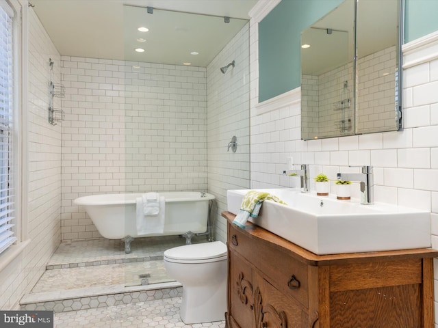 bathroom featuring a washtub, vanity, tile walls, tile patterned flooring, and toilet