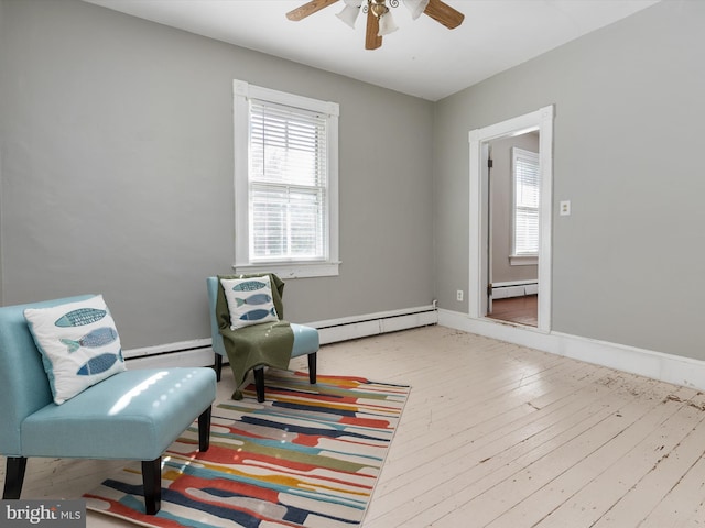 sitting room with ceiling fan, wood-type flooring, and a baseboard heating unit