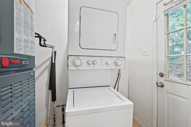 washroom with heating unit and stacked washer and clothes dryer