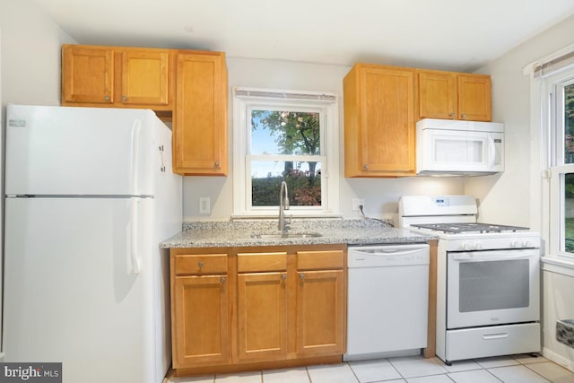 kitchen with white appliances, light tile patterned floors, sink, and plenty of natural light