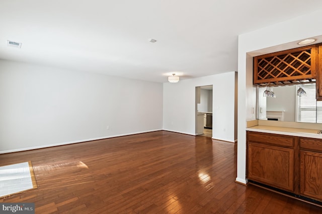 unfurnished living room featuring visible vents, dark wood-type flooring, and baseboards