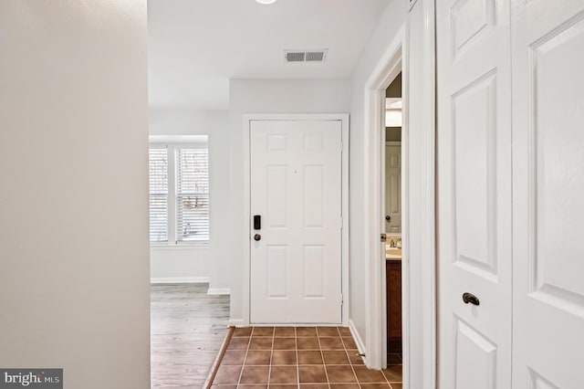 foyer featuring visible vents, baseboards, and dark tile patterned floors