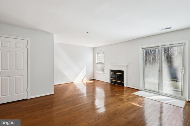 unfurnished living room featuring visible vents, baseboards, a glass covered fireplace, and wood-type flooring