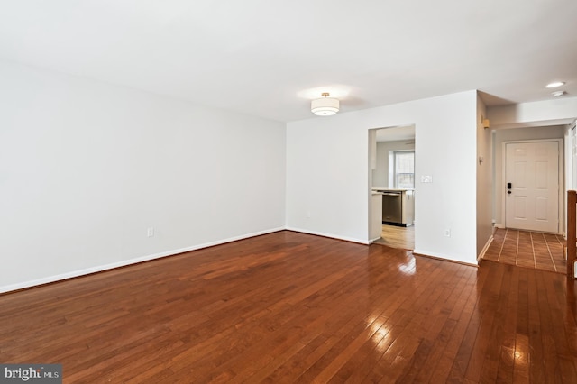 spare room with baseboards and dark wood-style flooring