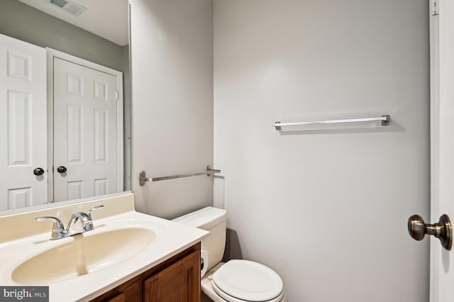 half bathroom featuring visible vents, toilet, and vanity