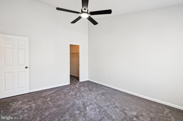 unfurnished bedroom featuring baseboards, carpet floors, a high ceiling, a spacious closet, and a closet