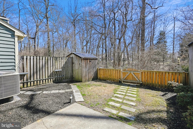 view of yard with central AC unit, an outdoor structure, a fenced backyard, and a gate