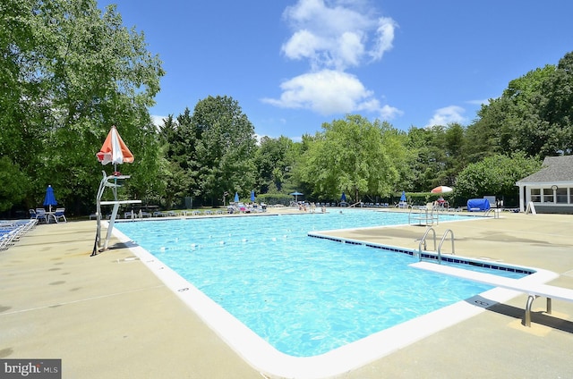 community pool with a diving board and a patio area