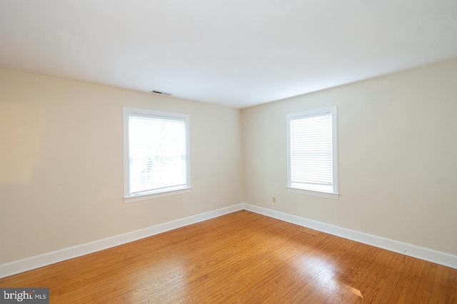 spare room featuring hardwood / wood-style flooring and a healthy amount of sunlight