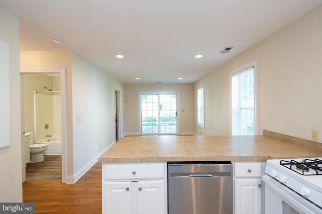 kitchen featuring stainless steel dishwasher, kitchen peninsula, light hardwood / wood-style flooring, and white cabinets