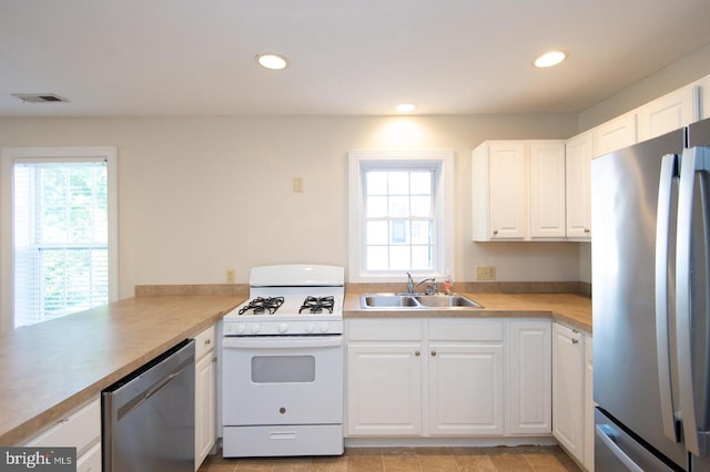 kitchen with appliances with stainless steel finishes, sink, kitchen peninsula, and white cabinetry